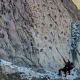 Zwei Personen schauen an einer Felswand empor, auf der Abdrücke zu sehen sind