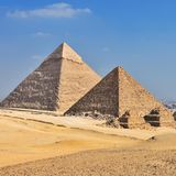 Die Pyramiden von Gizeh im Sonnenschein. Kairo zeichnet sich am Horizont im Hintergrund ab.