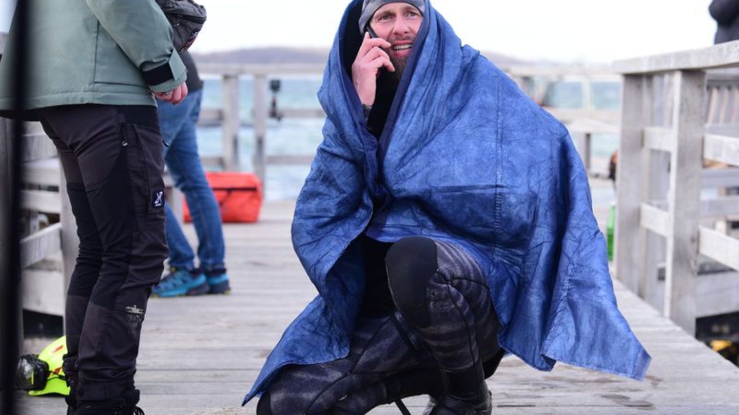 Robert Marc Lehmann geht auf Tuchfühlung mit einem gestrandeten Wal in der Ostsee. Foto: Daniel Bockwoldt/dpa