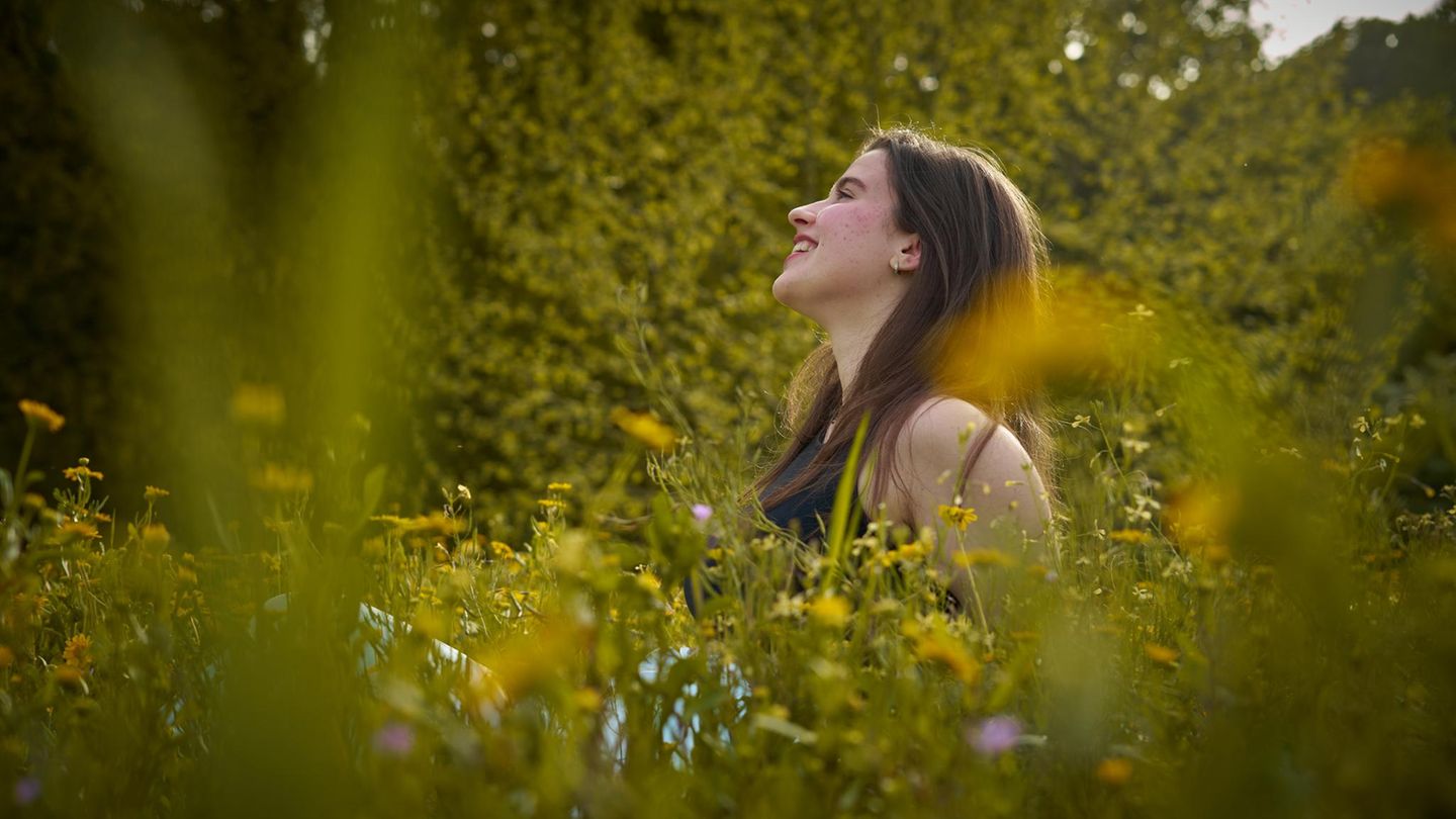 Frau sitzt in einer Wildblumenwiese