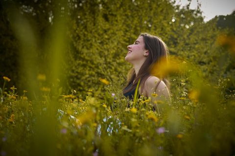 Frau sitzt in einer Wildblumenwiese