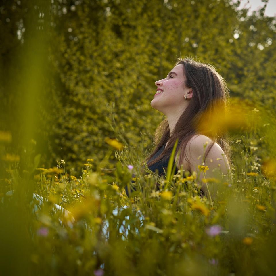 Frau sitzt in einer Wildblumenwiese