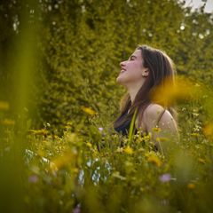 Frau sitzt in einer Wildblumenwiese