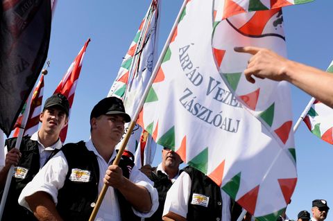 Eine Gruppe von Männern marschiert mit Fahnen im Sonnenlicht
