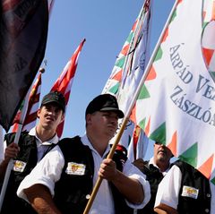 Eine Gruppe von Männern marschiert mit Fahnen im Sonnenlicht