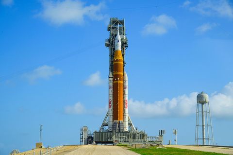 Auf der Startrampe in Florida steht die Rakete schon bereit. An ihrer Spitze ist die Orionkapsel (weiß) zu sehen, in der die Crew sitzen wird. Darunter das Space Launch System (orange, mit weißen "Boostern"), das die Kapsel von der Erde tragen und auf ihre Reise Richtung Mond schubsen soll