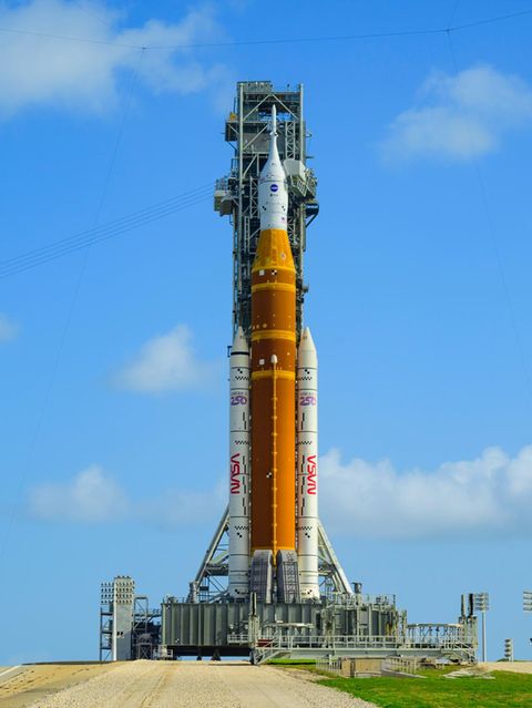 Auf der Startrampe in Florida steht die Rakete schon bereit. An ihrer Spitze ist die Orionkapsel (weiß) zu sehen, in der die Crew sitzen wird. Darunter das Space Launch System (orange, mit weißen "Boostern"), das die Kapsel von der Erde tragen und auf ihre Reise Richtung Mond schubsen soll