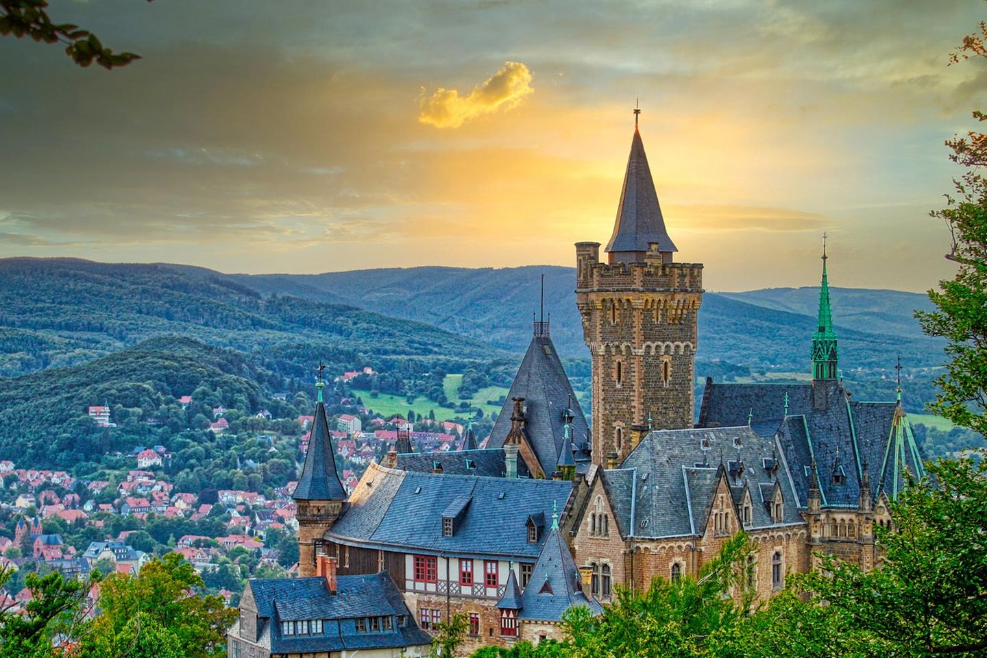 Schloss Wernigerode vor goldenem Himmel, im Hintergrund Hügel