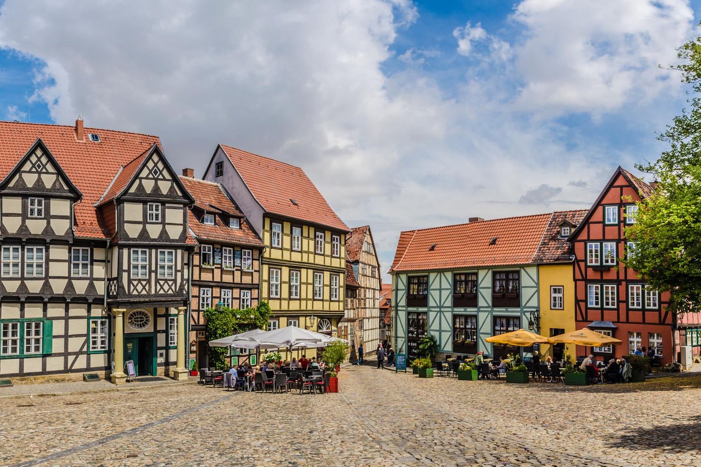 Fachwerkhäuser und Platz mit Gastronomie und Sonnenschirmen in Quedlinburg