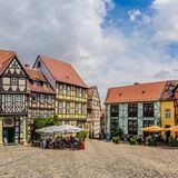 Fachwerkhäuser und Platz mit Gastronomie und Sonnenschirmen in Quedlinburg