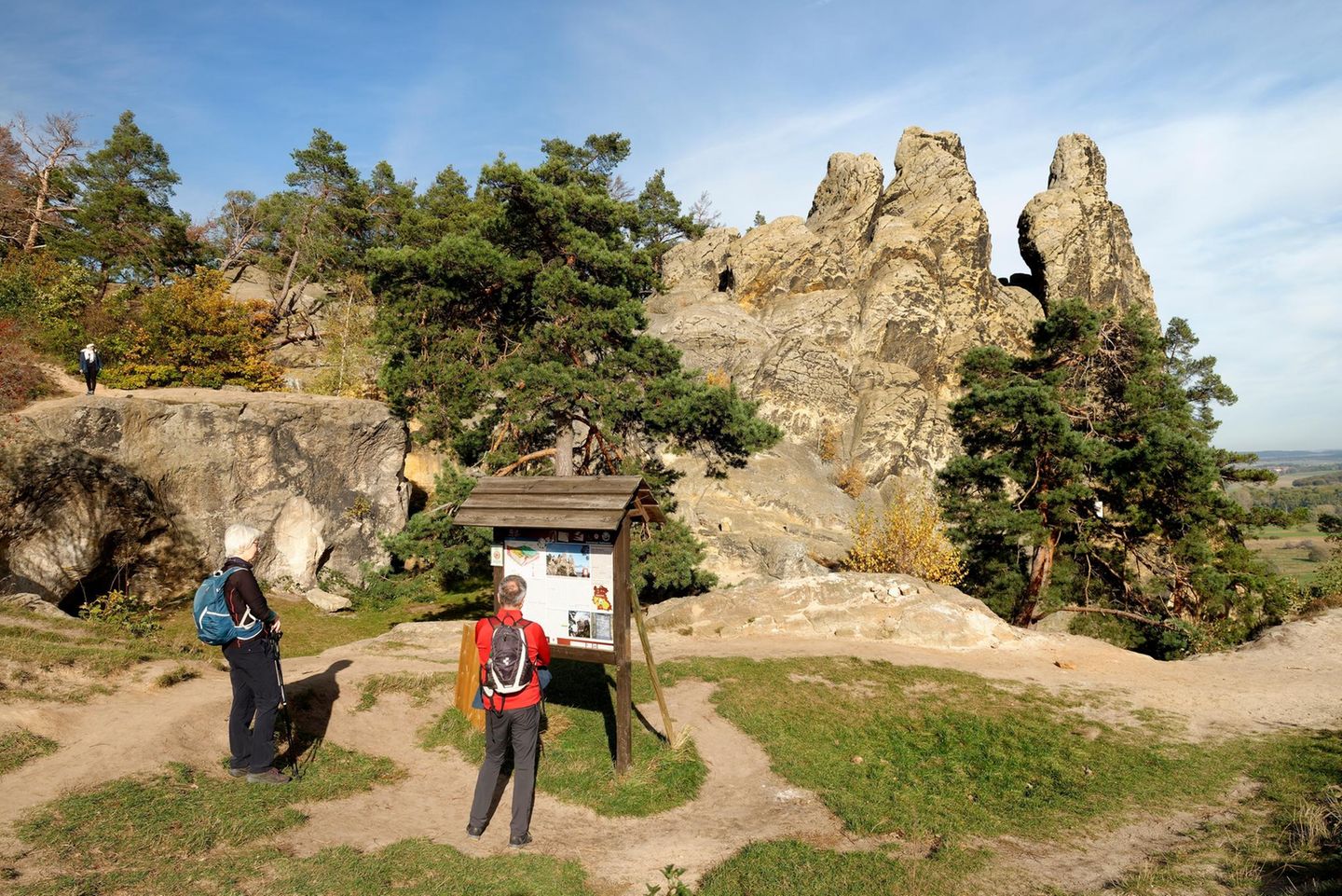 Felsgruppe Hamburger Wappen, davor zwei Wandernde vor Schild