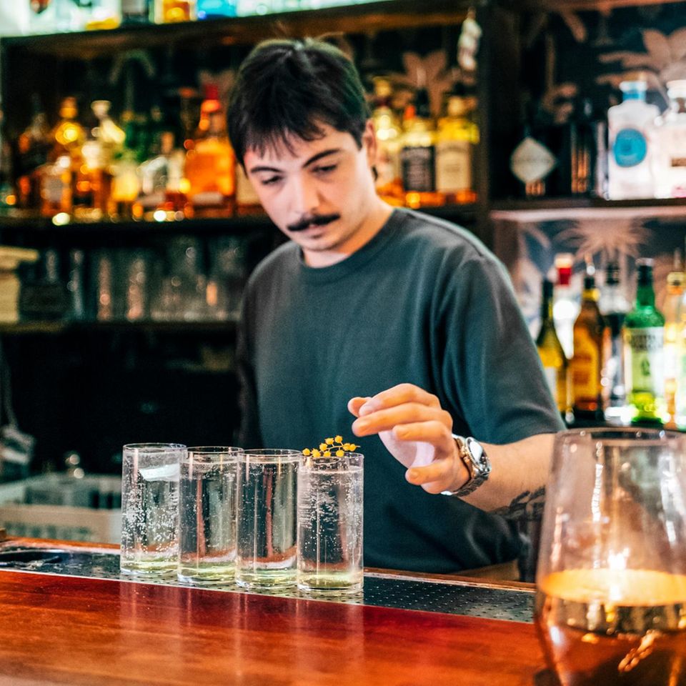 Barkeeper in einer Bar mit Drinks vor sich