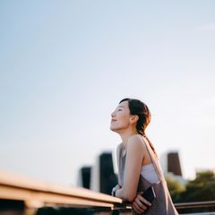 Eine junge Person lehnt an einem geländer und hat sie Augen geschlossen