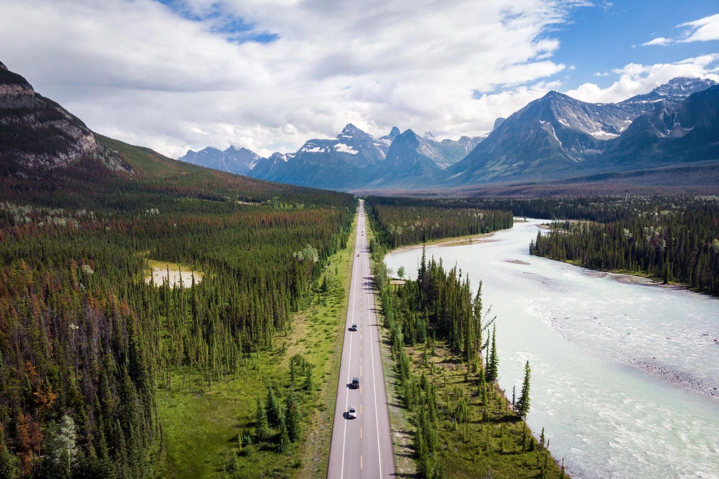 Luftbild vom von Bäumen gerahmten Icefields Parkway, im Hintergrund Berge