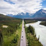 Luftbild vom von Bäumen gerahmten Icefields Parkway, im Hintergrund Berge