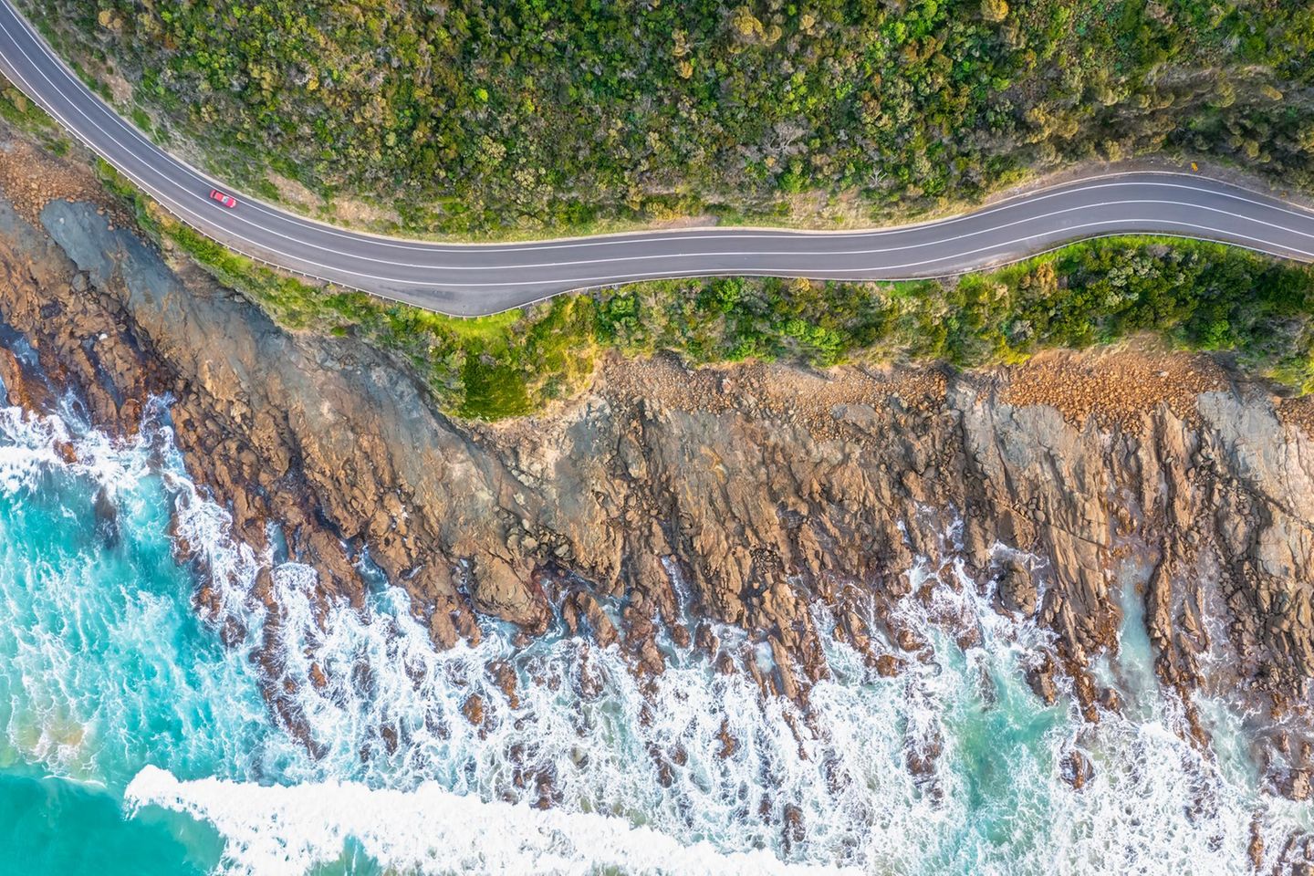 Straße Great Ocean Road zwischen grüner Landschaft, Felsen und Meer