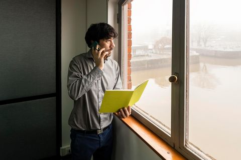 Mann mit Notizbuch im Büro schaut nachdenklich