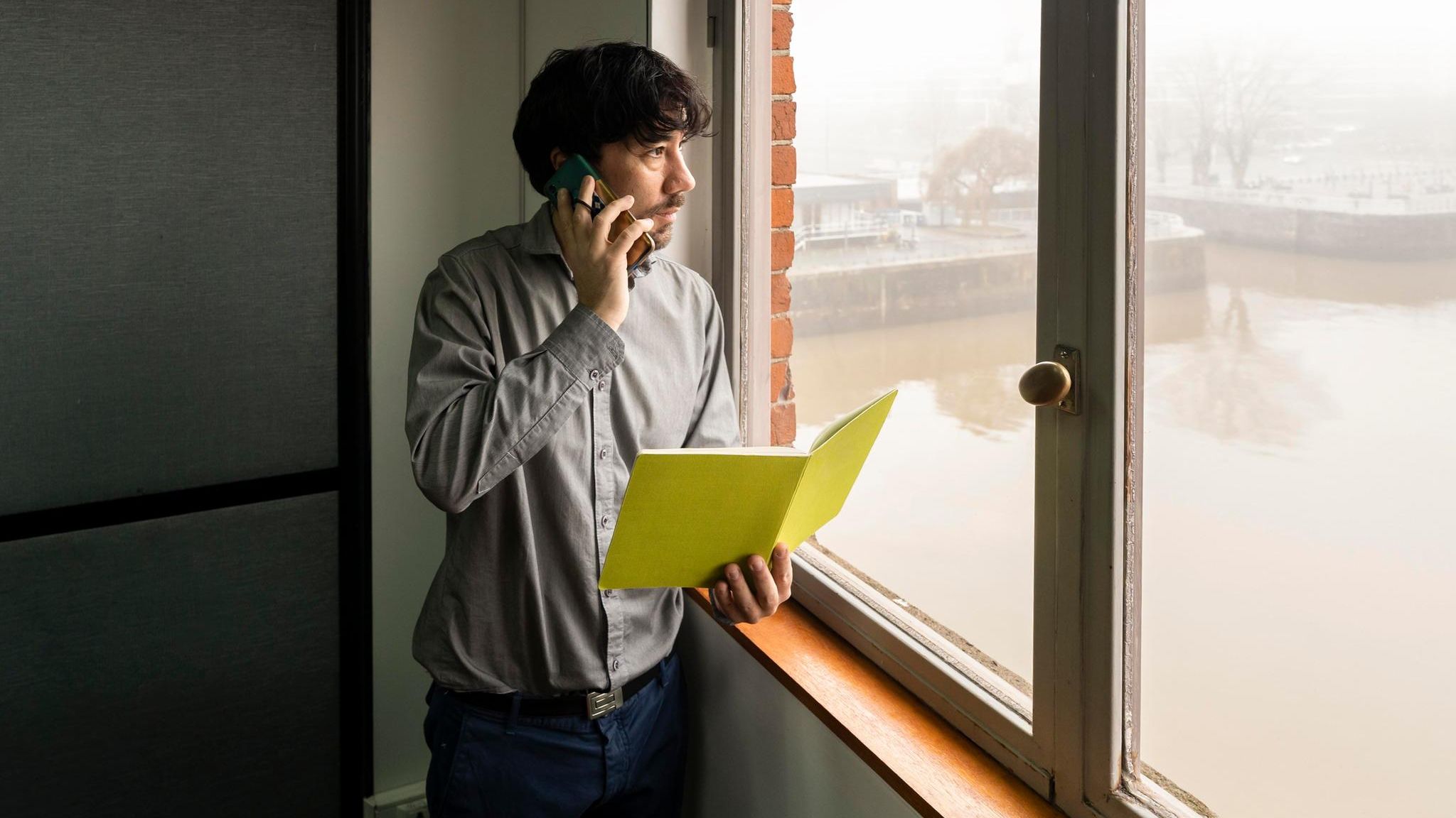 Mann mit Notizbuch im Büro schaut nachdenklich