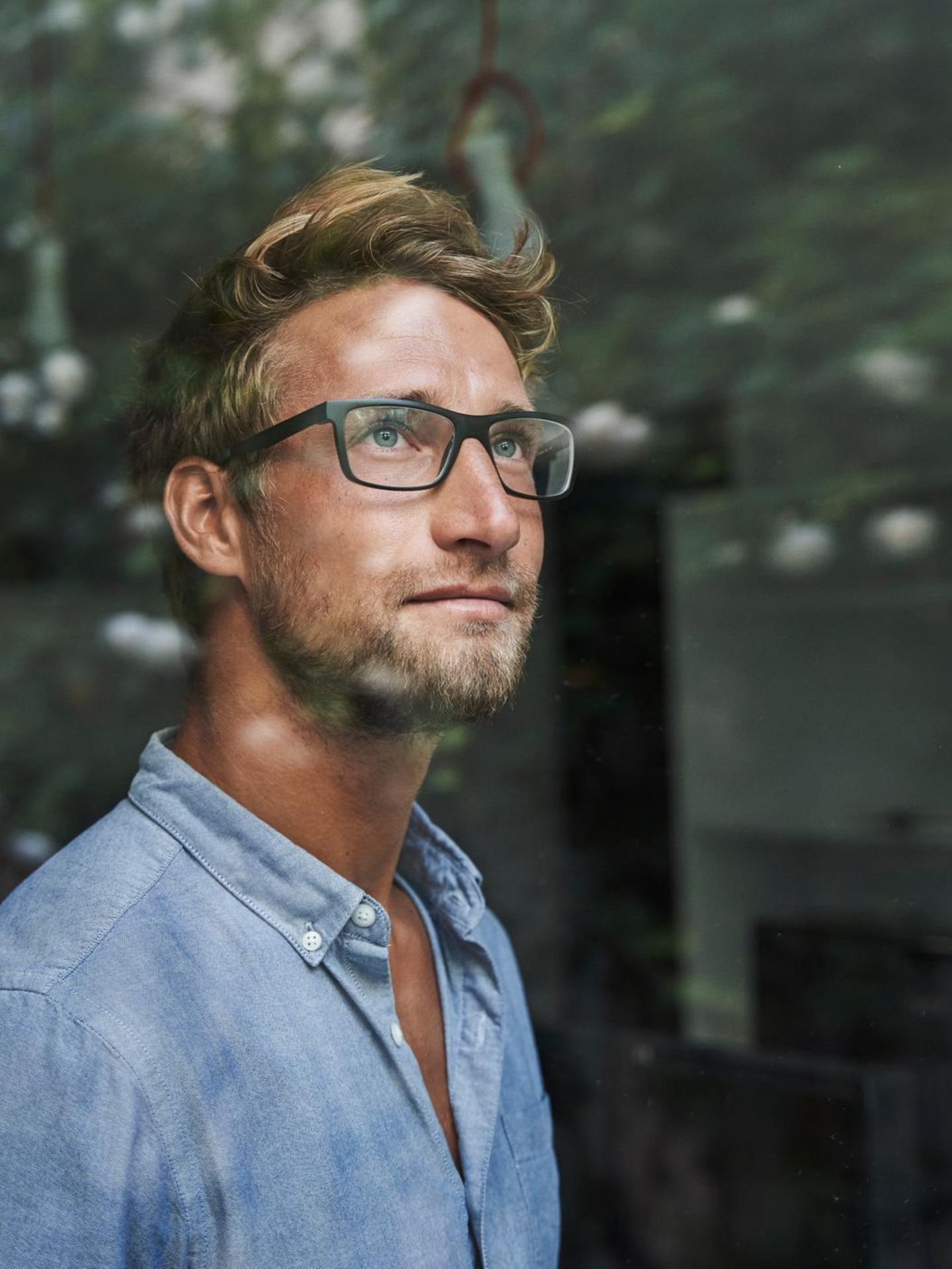 Junger Mann im Büro guckt durch eine Glasscheibe