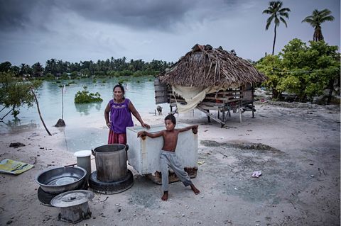 Frau und Kind stehen vor überflutetem Dorf