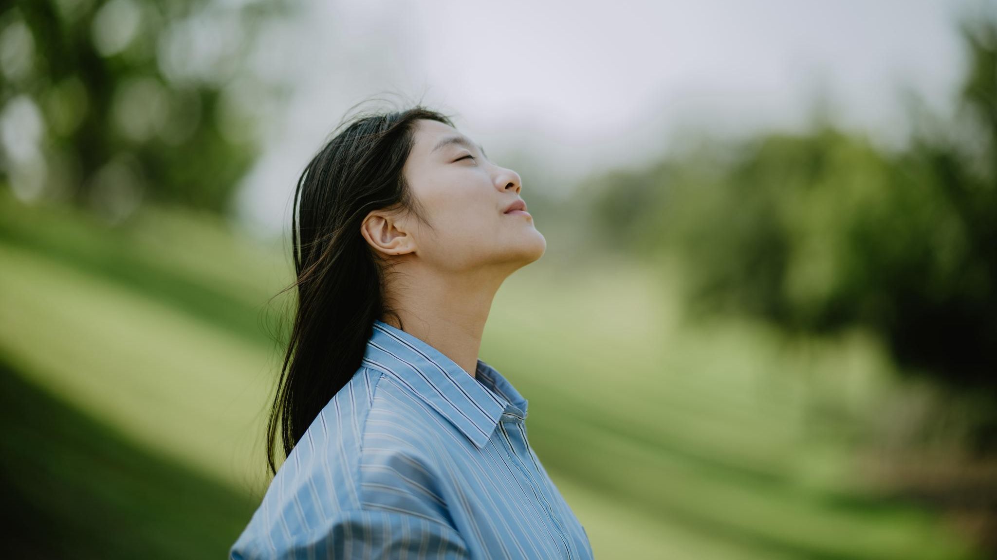 Eine Person hält ihr Gesicht mit geschlossenen Augen der Sonne entgegen