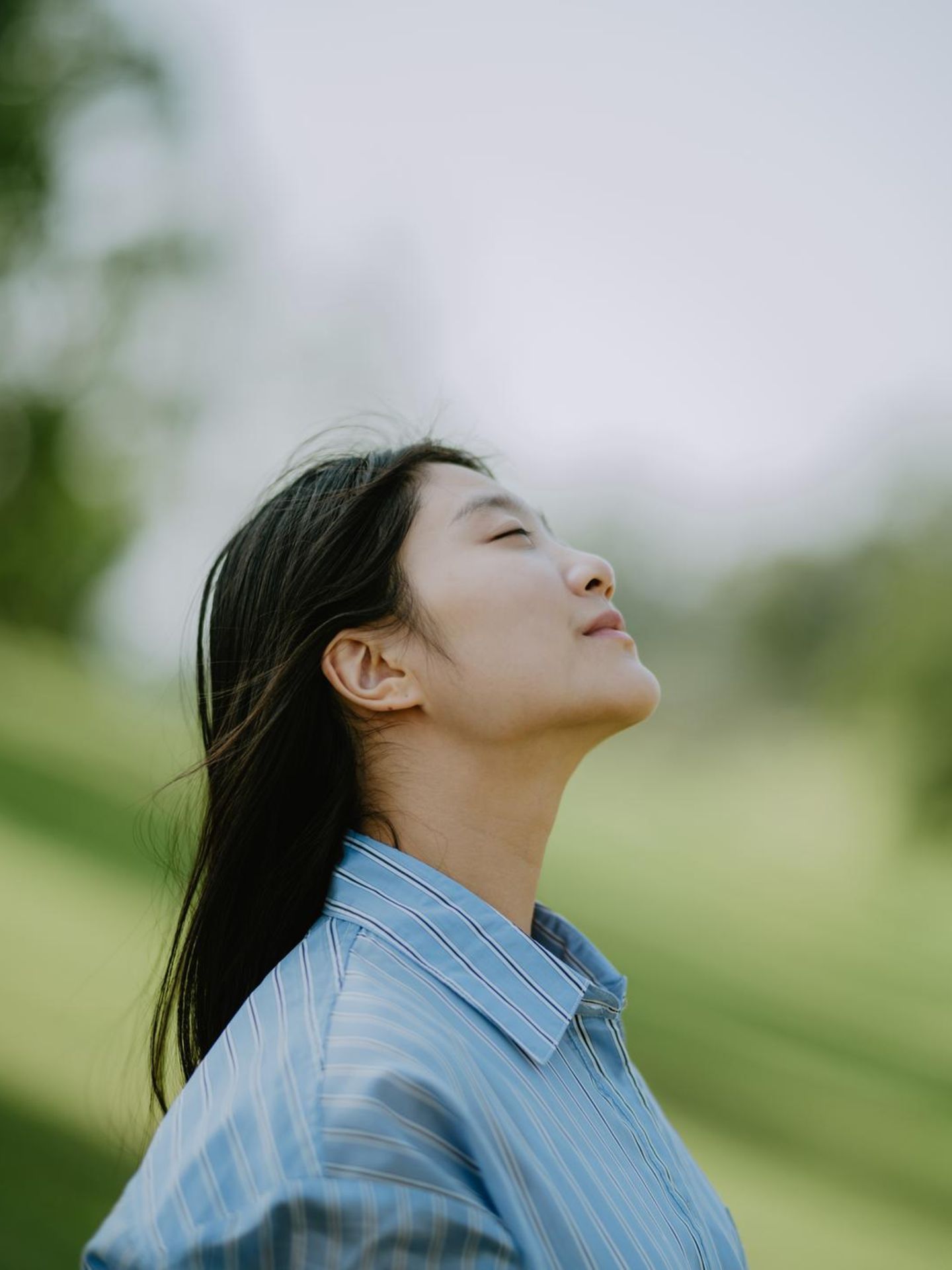 Eine Person hält ihr Gesicht mit geschlossenen Augen der Sonne entgegen