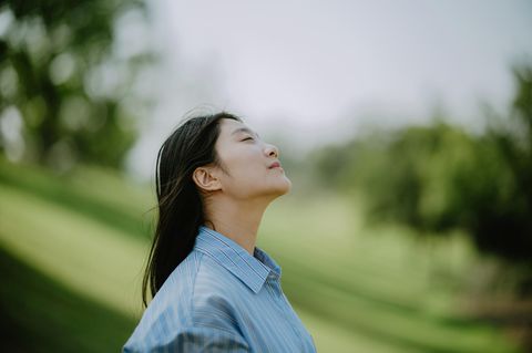 Eine Person hält ihr Gesicht mit geschlossenen Augen der Sonne entgegen