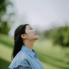 Eine Person hält ihr Gesicht mit geschlossenen Augen der Sonne entgegen