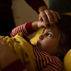 Eine Mutter hält ihre Hand auf die Stirn ihrer Tochter
