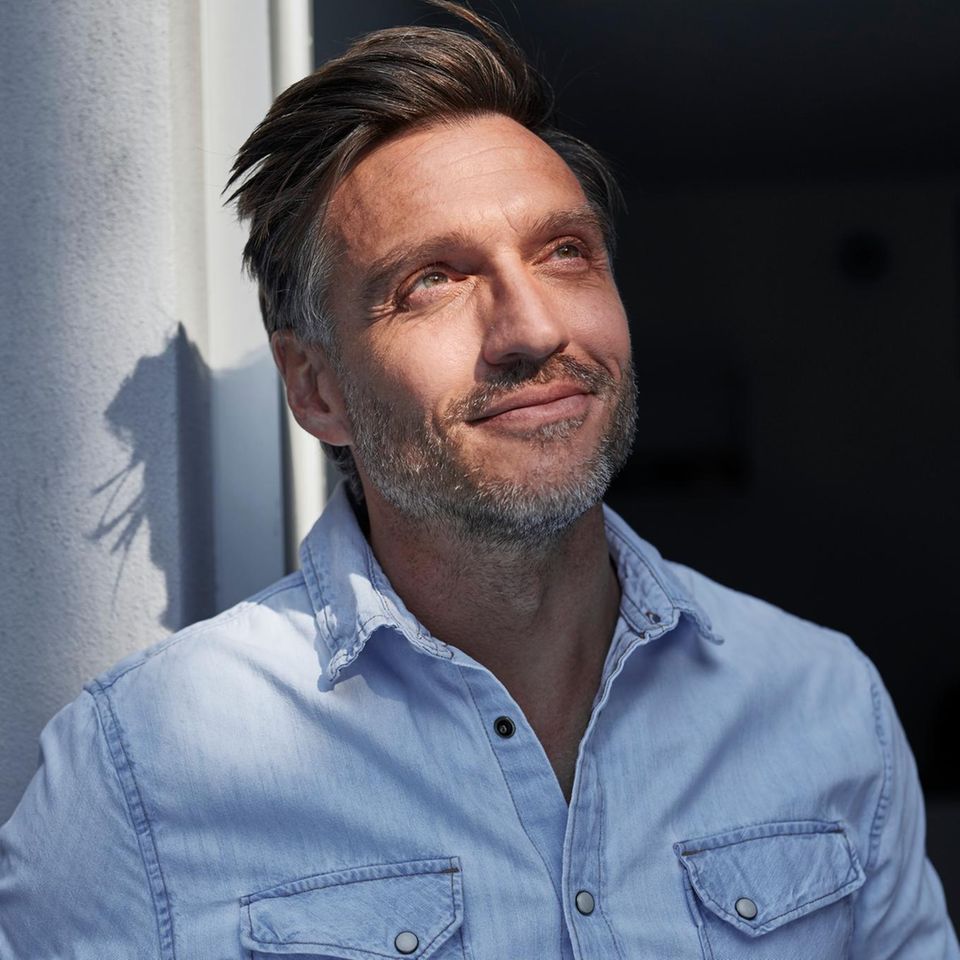 Eine Person schaut lächelnd der Sonne entgegen