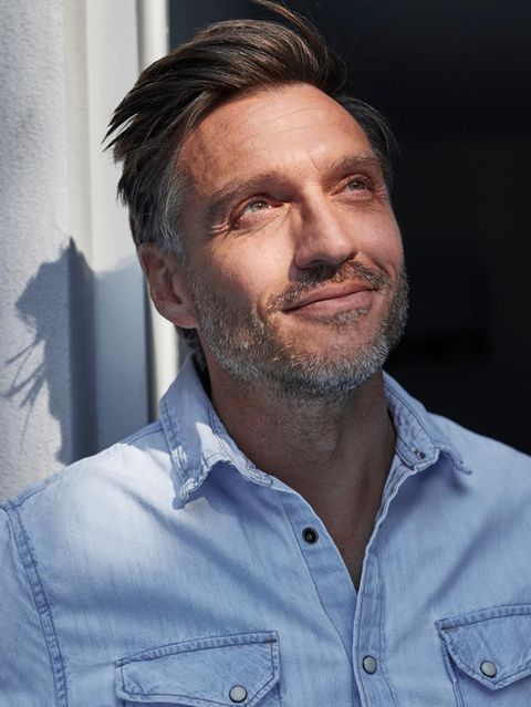 Eine Person schaut lächelnd der Sonne entgegen