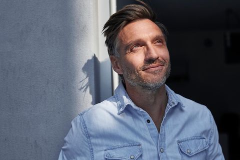 Eine Person schaut lächelnd der Sonne entgegen