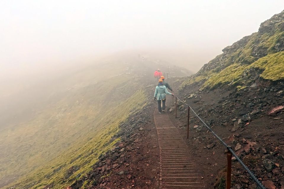 Menschen laufen durch Vulkanlandschaft auf Island