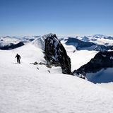 Blick auf den schneebedeckten Berg Galdhøpiggen mit Skifahrer