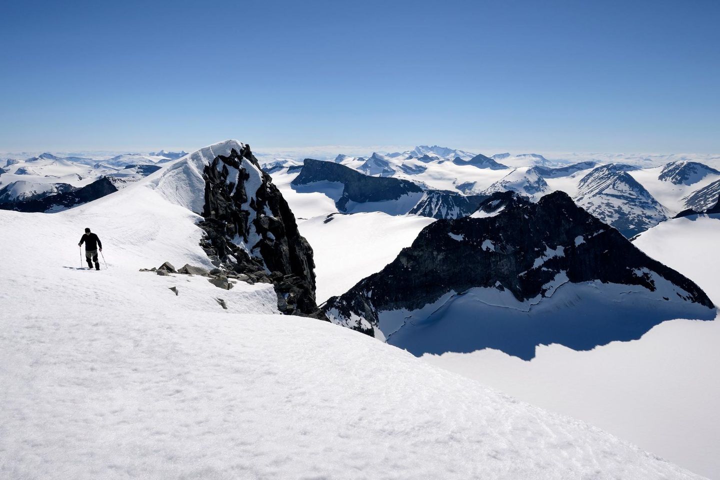 Blick auf den schneebedeckten Berg Galdhøpiggen mit Skifahrer
