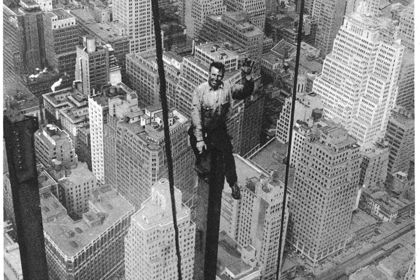 Ein Bauarbeiter sitzt auf einem Stahlträger in mehreren Metern Höhe über der Skyline von New York