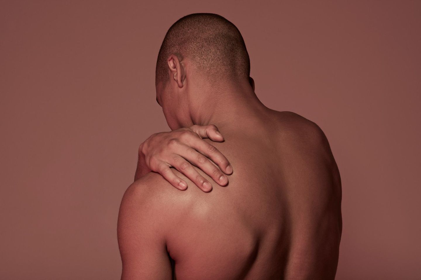 Mann fasst sich an die Schulter