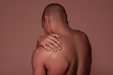 Mann fasst sich an die Schulter