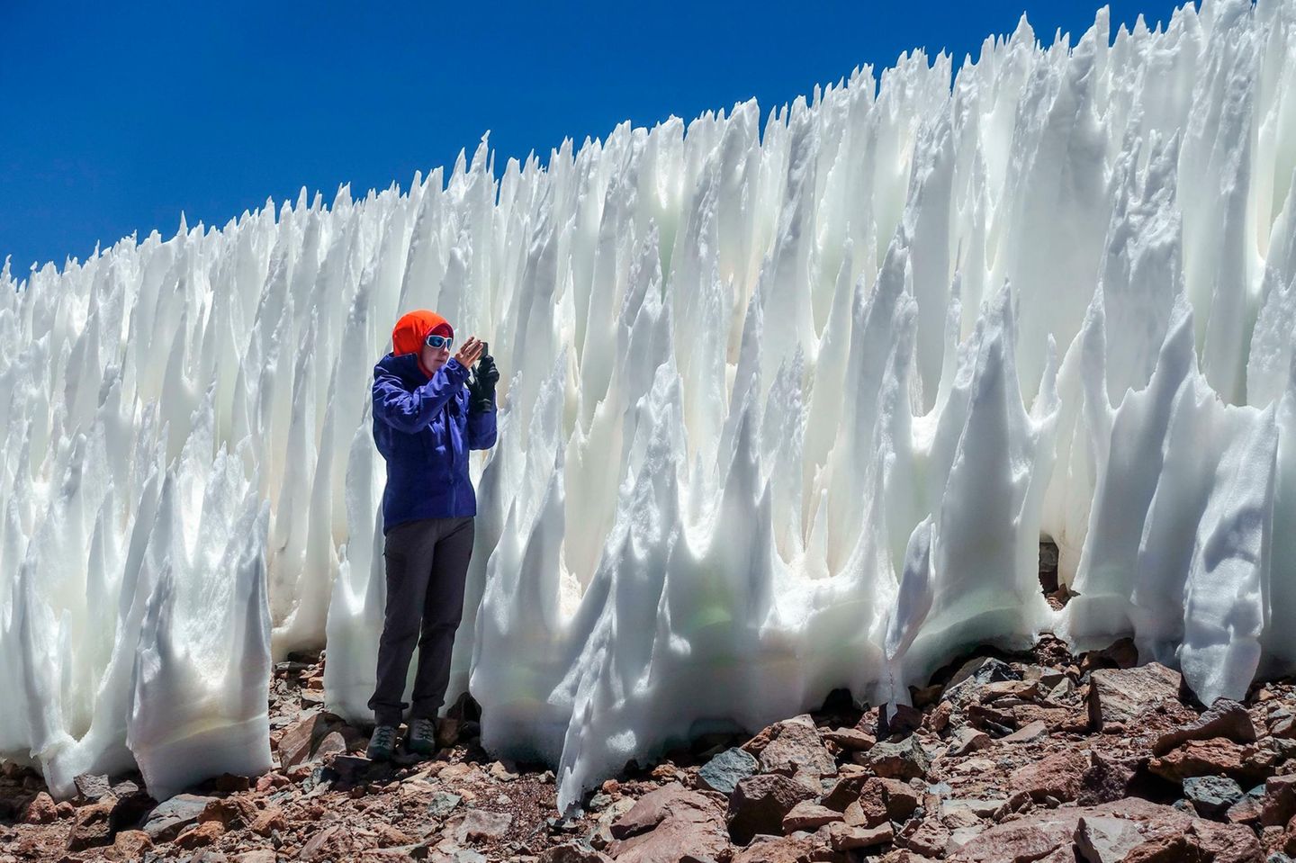 Die übermannshohen Eissäulen in der Atacama-Wüste wirken, als habe ein Magier sie aus dem Boden wachsen lassen. In Wahrheit sind sie Reste einer Schneedecke: Sie entstehen in kalten, sonnigen Hochwüsten, wenn Eis unregelmäßig abtaut. An ihren Spitzen reißen sich Wassermoleküle nur langsam los; weiter unten lassen Feuchtigkeit und gebündeltes Sonnenlicht den Schnee schnell schmelzen. Die Strukturen heißen Büßereis ("Penitentes"), nach den hohen, spitzen Hüten einer katholischen Bruderschaft.
