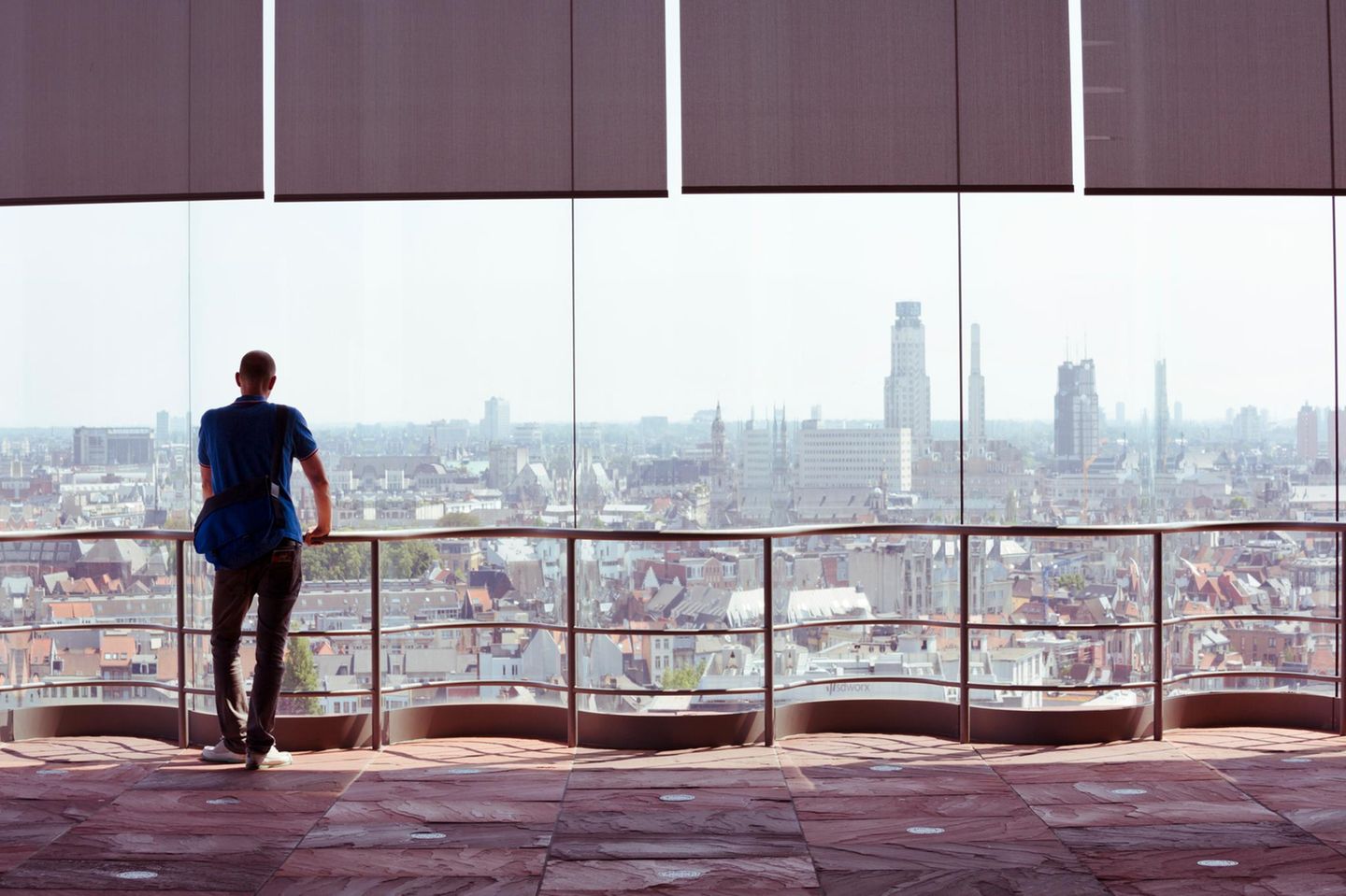 Mann blickt auf Dächer und Skyline von Antwerpen aus dem Museum Aan de Stroom