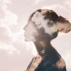 Feinstaub: Ein Frauenkopf ist an einem klaren Sommertag von Wolken umhüllt