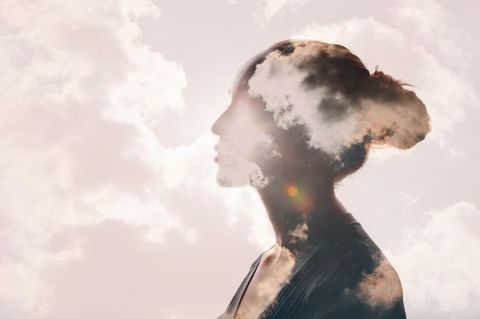 Feinstaub: Ein Frauenkopf ist an einem klaren Sommertag von Wolken umhüllt