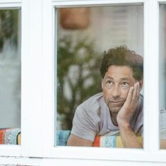 Mann guckt aus dem Fenster