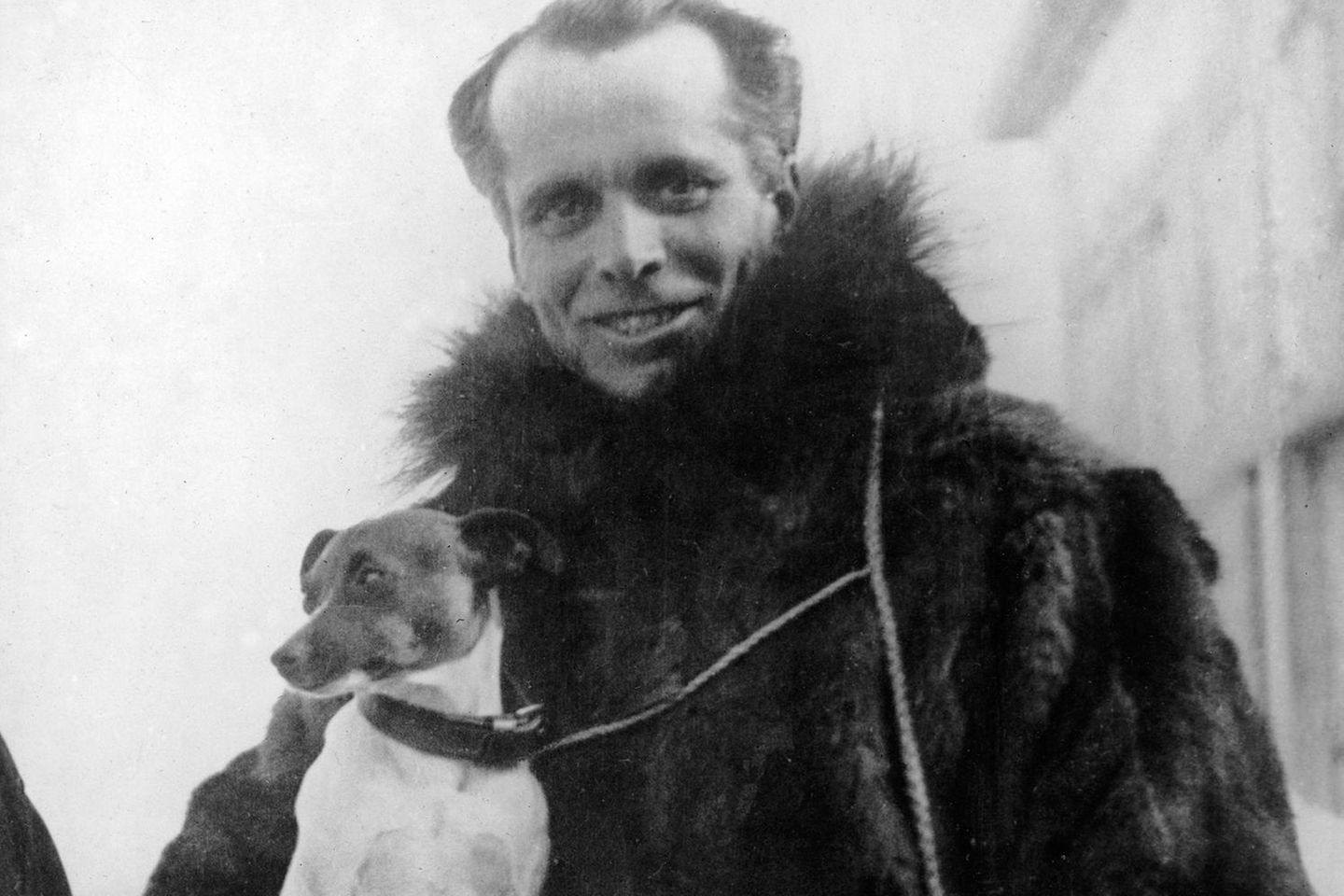 In warmer Kleidung sieht Umberto Nobile mit seinem Hund auf dem Arm in die Kamera.