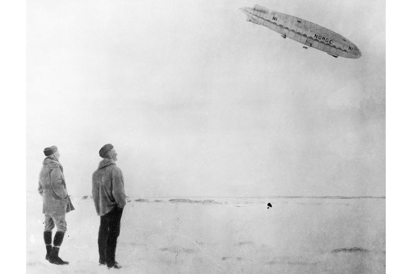 Amundsen und Ellsworth betrachten vom Boden aus die "Norge" am Himmel.