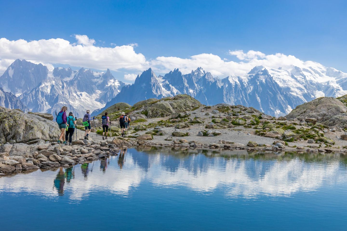 Wandergruppe vor Bergkulisse in den Alpen, im Vordergrund Wasser