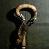 Ein Stock, geschnitzt von Molfar Mychajlo Nechaj: Der Heiler arbeitete mit diesem Stab, in den drei Totemtiere eingeschnitten sind – Adler, Schlange und Wolf. Der Adler steht in vielen osteuropäischen Traditionen für Weitblick und Verbindung zum Himmel, die Schlange für Erneuerung und Heilkraft, der Wolf für Stärke und Schutz der Gemeinschaft. Der Stock bündelt so jene Kräfte, auf die sich Nechaj in seinen Ritualen stützte. Er wird heute in einem Museum aufbewahrt