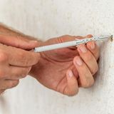 Person dreht Dübel in Wand