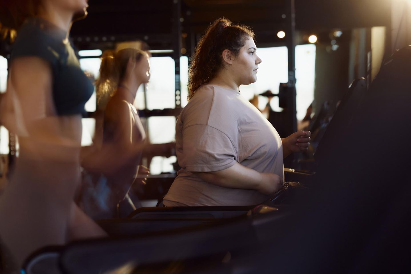 Junge übergewichtige Frau, die auf einem Laufband in einem Fitnessstudio trainiert