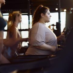 Junge übergewichtige Frau, die auf einem Laufband in einem Fitnessstudio trainiert